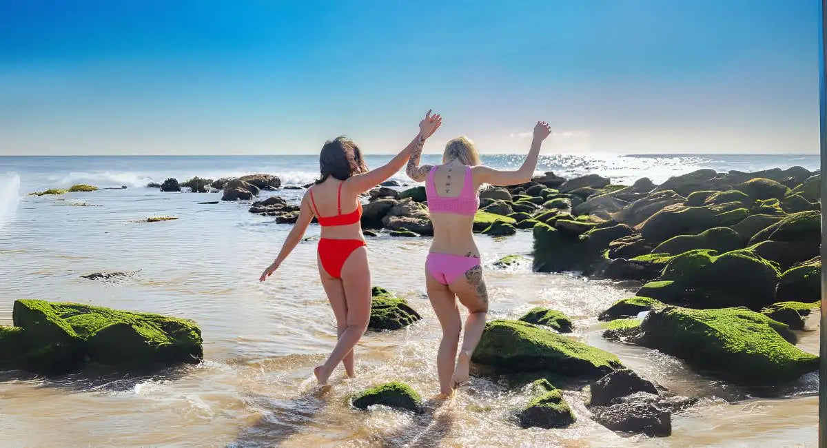 Two friends enjoying the ocean with sun-kissed hair, embodying carefree summer vibes powered by Suntied Leave In conditioner.